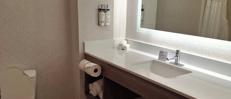 Une salle de bain moderne équipée d’un WC, d’un lavabo, d’un miroir et d’un porte-serviettes.