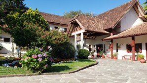 Un edificio tradicional con tejado de tejas, patio empedrado y plantas en macetas.