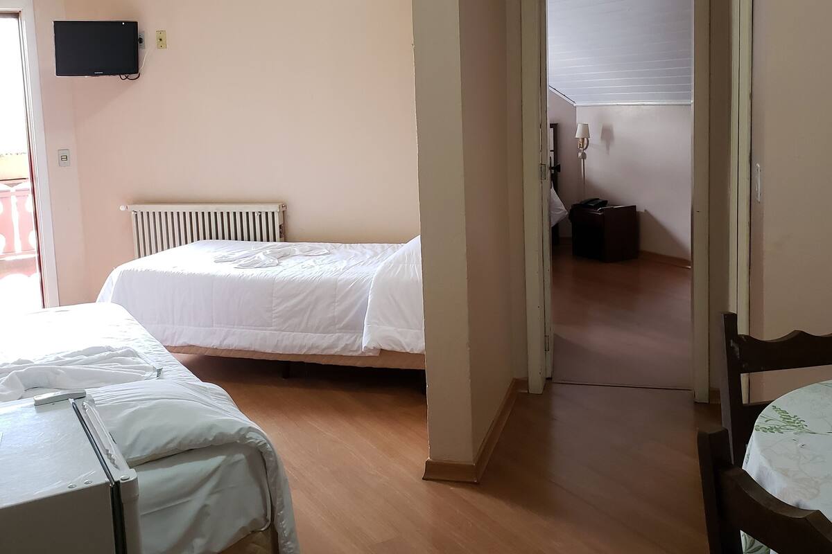 Un dormitorio con dos camas, un radiador, un televisor montado en la pared y suelo de madera.