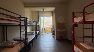 Habitación tipo dormitorio con literas, un radiador, un espejo y vistas a un espacio exterior por una puerta.