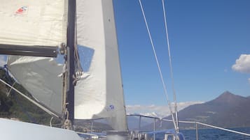 Un voilier à voile blanche, offrant une vue dégagée sur l’eau et les montagnes en arrière-plan.