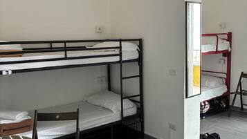 Quarto tipo dormitório com beliches, escrivaninha, cadeira e lixeira.