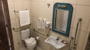 A bathroom with a toilet, sink, and hand dryer. There is a mirror with a blue frame and a towel rack.