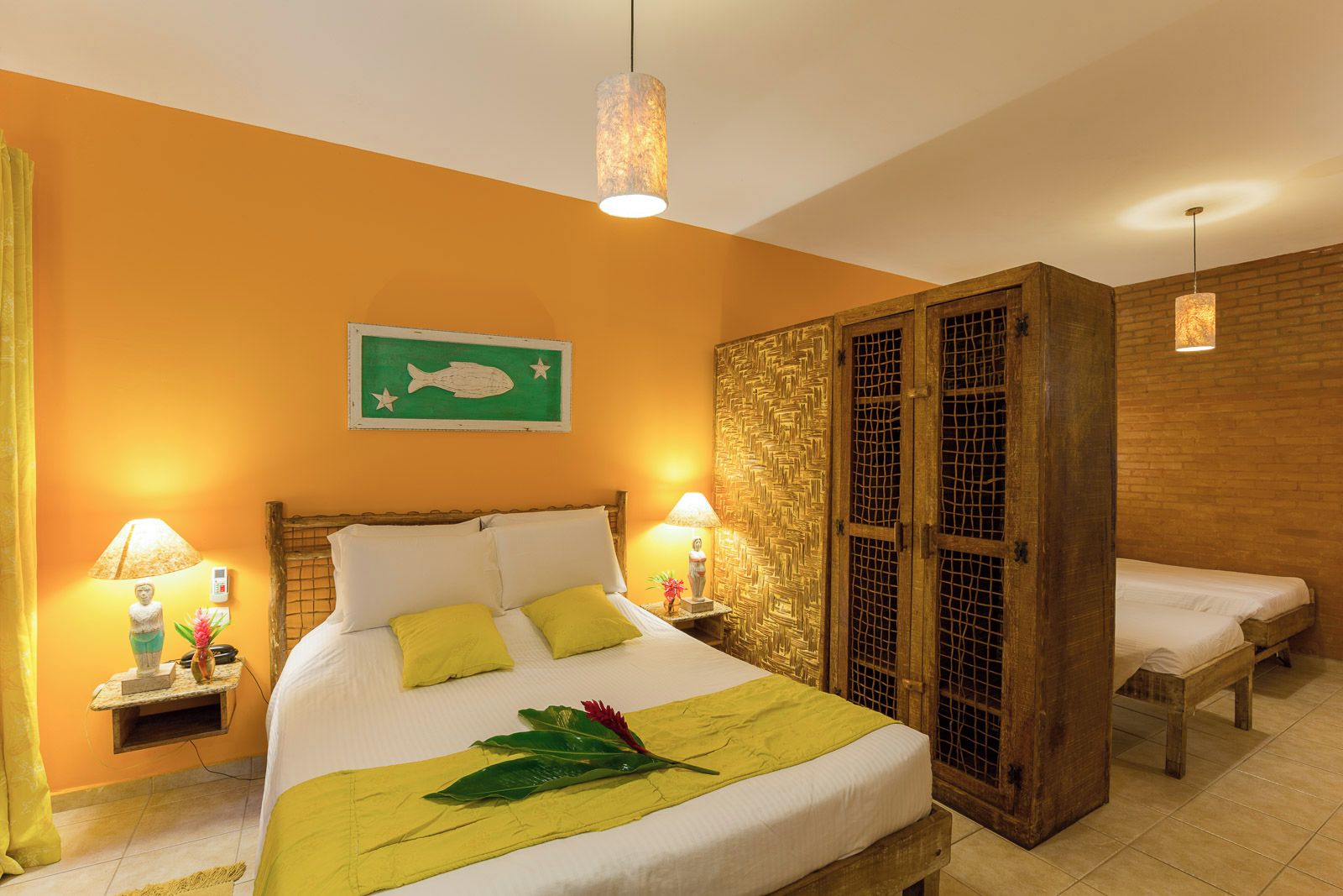 A hotel room with a bed, two bedside tables, a decorative wall hanging, and a wooden wardrobe.