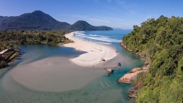 Di pantai, pasir putih, payung pantai, dan handuk pantai