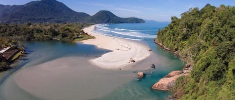 Na praia, areia branca, guarda-sóis, toalhas de praia 