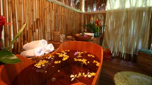 A wooden bathtub filled with water and flowers, surrounded by bamboo walls and a wooden floor. - Itamambuca Eco Resort (Ubatuba)
