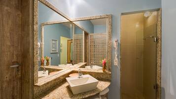 A bathroom with a large mirror, two sinks, a shower area, and a wooden door.