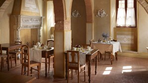 A dining area with multiple tables and chairs, brick arches, and a fireplace. - B&B Borgo Petrognano - Residenza d'epoca (Barberino Tavarnelle)