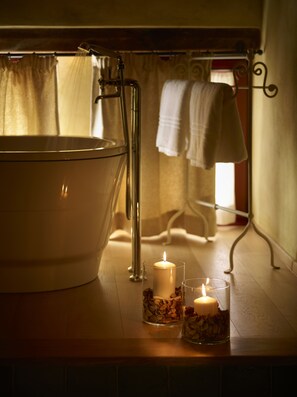 A bathroom with a bathtub, two candles, and a glass container with dried flowers. - B&B Borgo Petrognano - Residenza d'epoca (Barberino Tavarnelle)