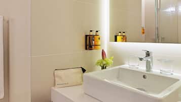 Un baño moderno con un lavabo grande de color blanco, cabina de ducha con mampara de vidrio y un espejo sobre el lavabo.