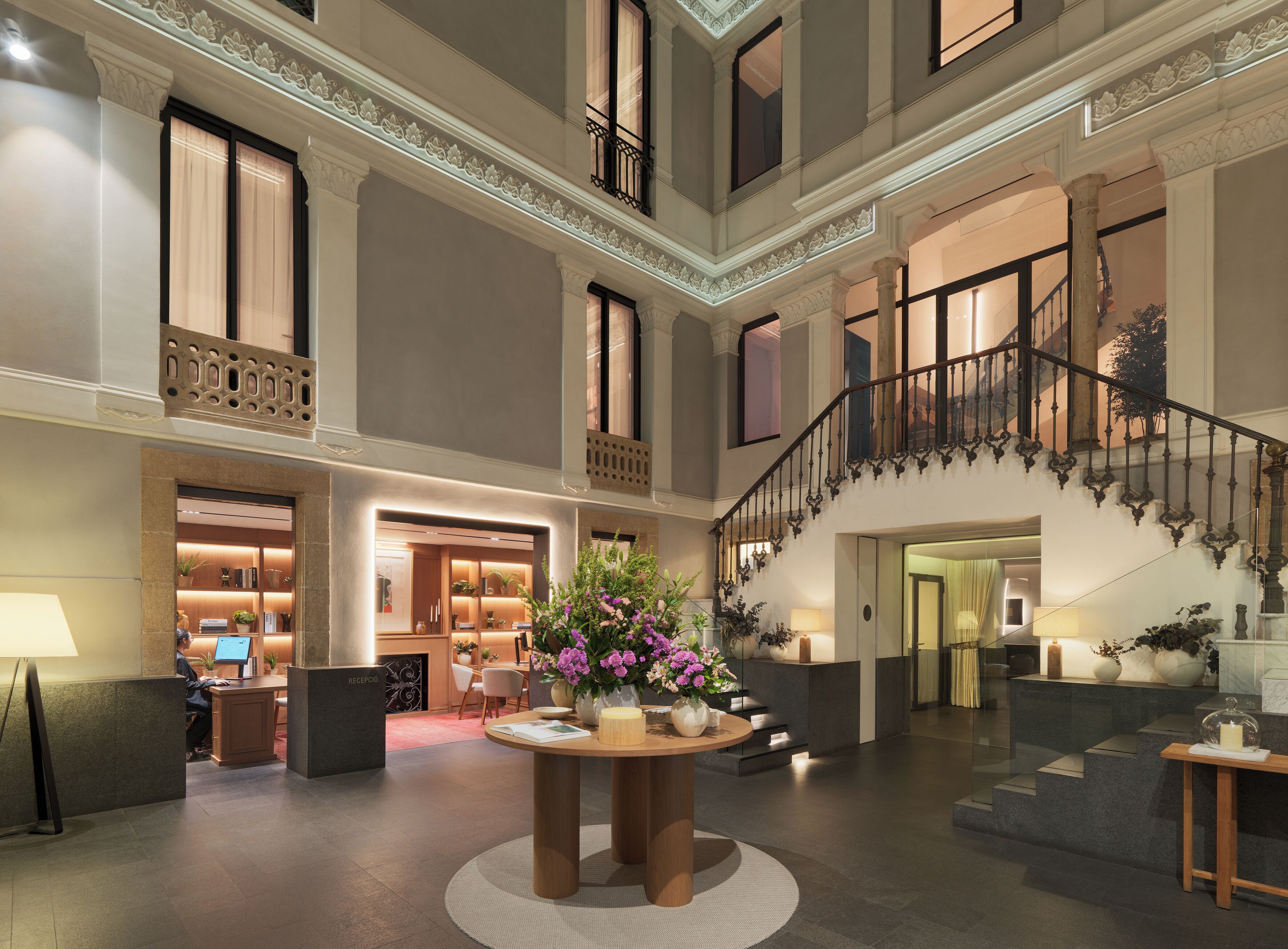 Eine prachtvolle Lobby mit Treppe, Rezeption und Sitzbereich.