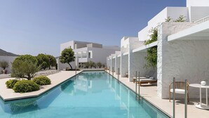 A modern pool area with a clear pool, white buildings, and outdoor seating. - Patmos Aktis, a Luxury Collection Resort & Spa, Greece (Patmos)