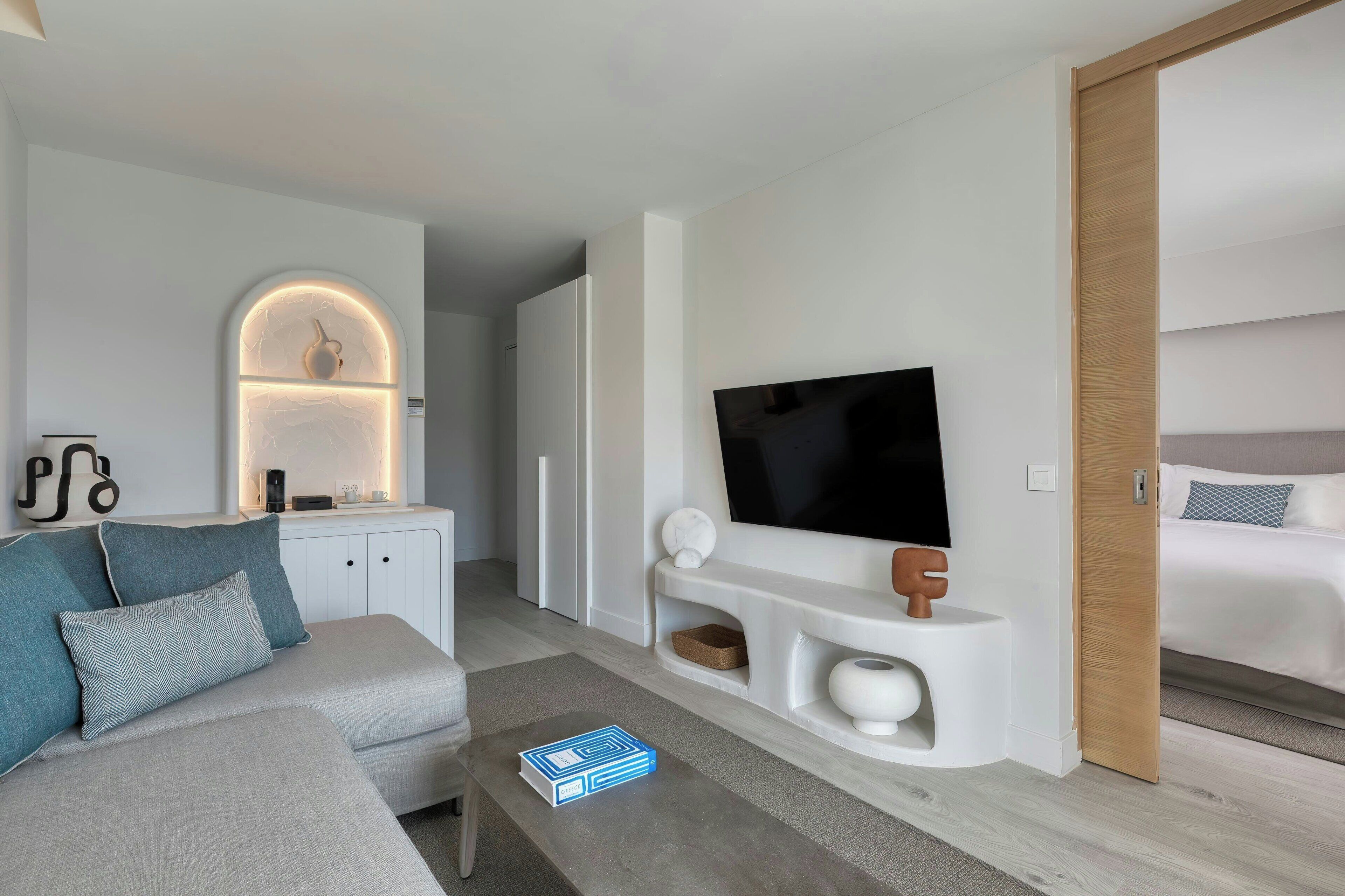Una sala de estar moderna con un sofá, una mesa de centro, un televisor de pantalla plana y un diseño minimalista.