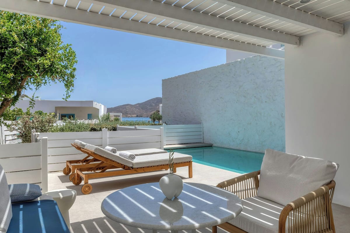 Ein sonniger Außenbereich mit Liegebereich, Pool und Tisch.