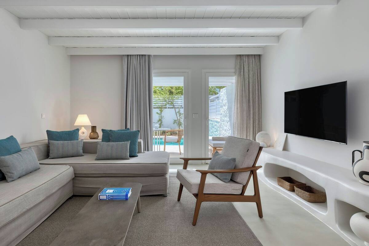 Ein modernes Wohnzimmer mit einer Couch, einem Sessel und einem Flachbildfernseher.