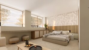 Un dormitorio moderno con una cama grande, un área de descanso con otomanas, una mesita con un libro y una vela, y vistas a árboles a través de amplios ventanales.