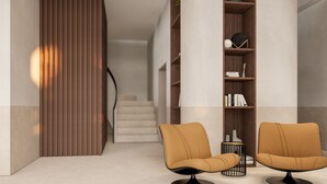 Un interior moderno con dos sillones de cuero, una estantería de madera y una escalera.