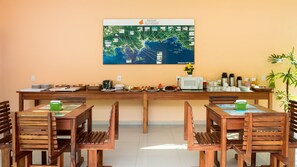 A dining area with a long table, chairs, and a map on the wall. - Pousada Villa Piemonte (Ubatuba)