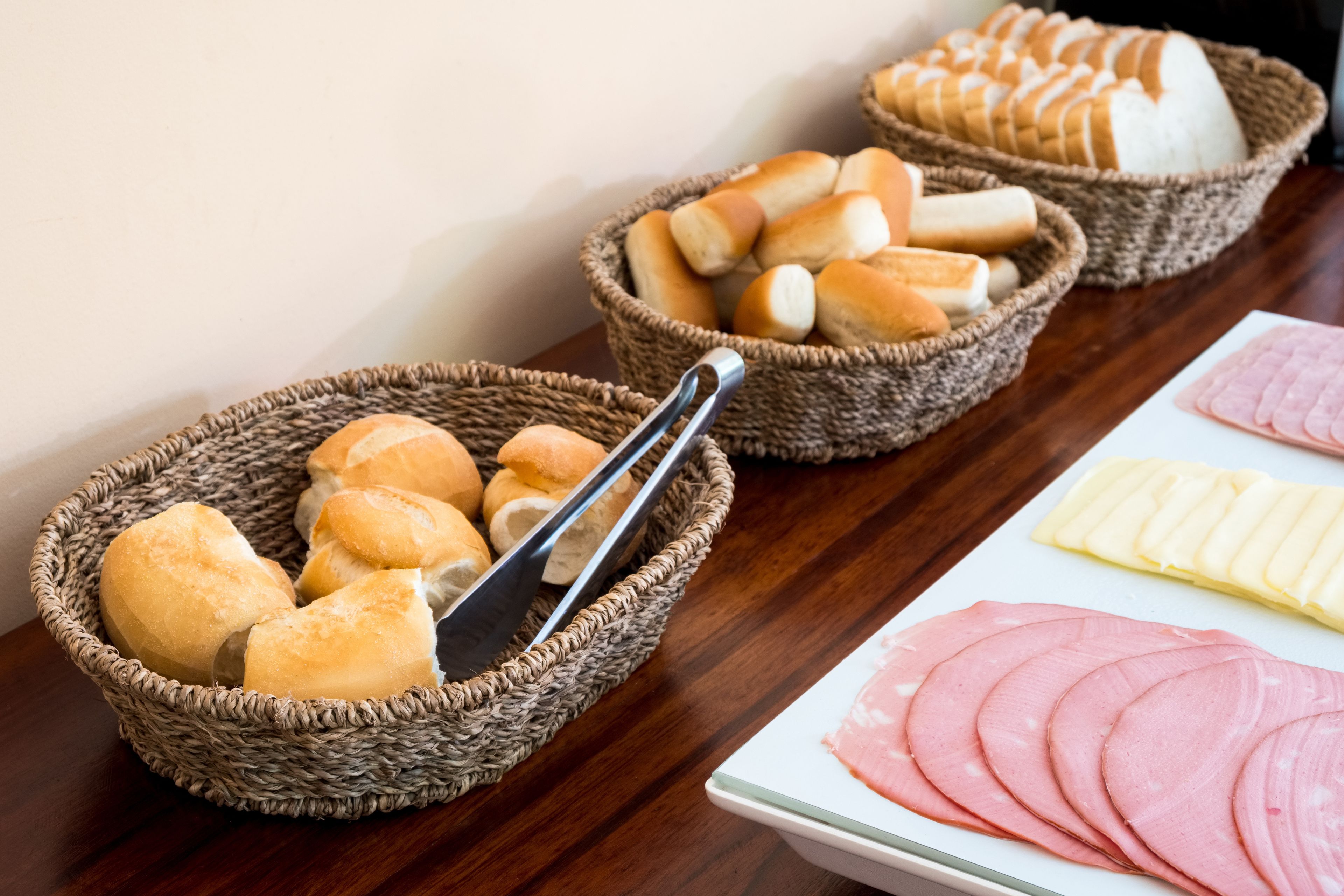Uma mesa com cestas de pão e fatias de presunto.