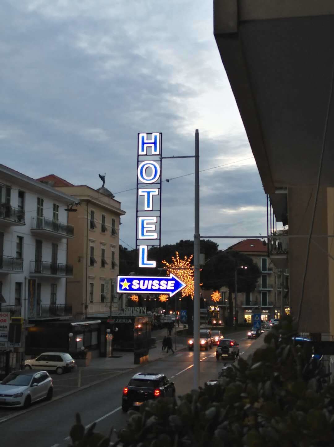 A hotel sign with a neon sign indicating direction to Switzerland.