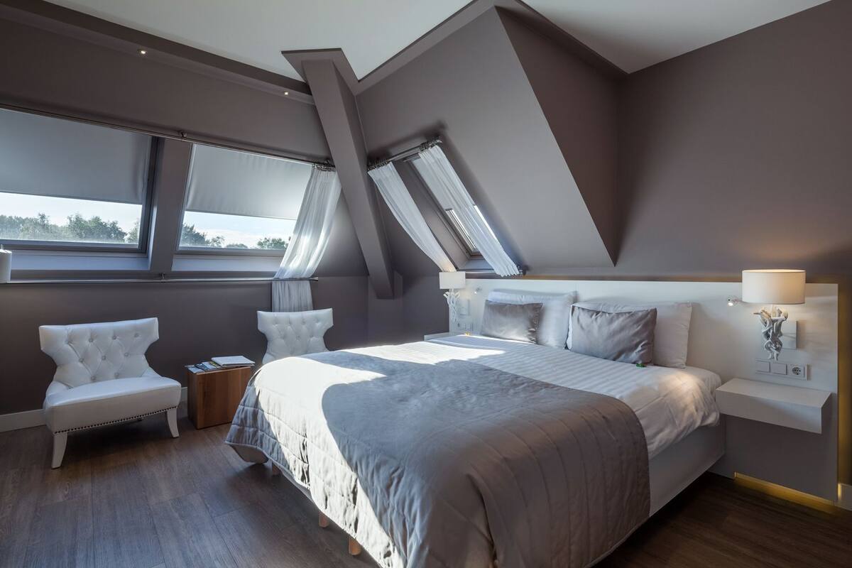 Un dormitorio moderno con una cama grande, una zona de estar y un tragaluz.