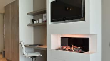 A modern home office with a built-in TV, fireplace, and a desk with a chair.