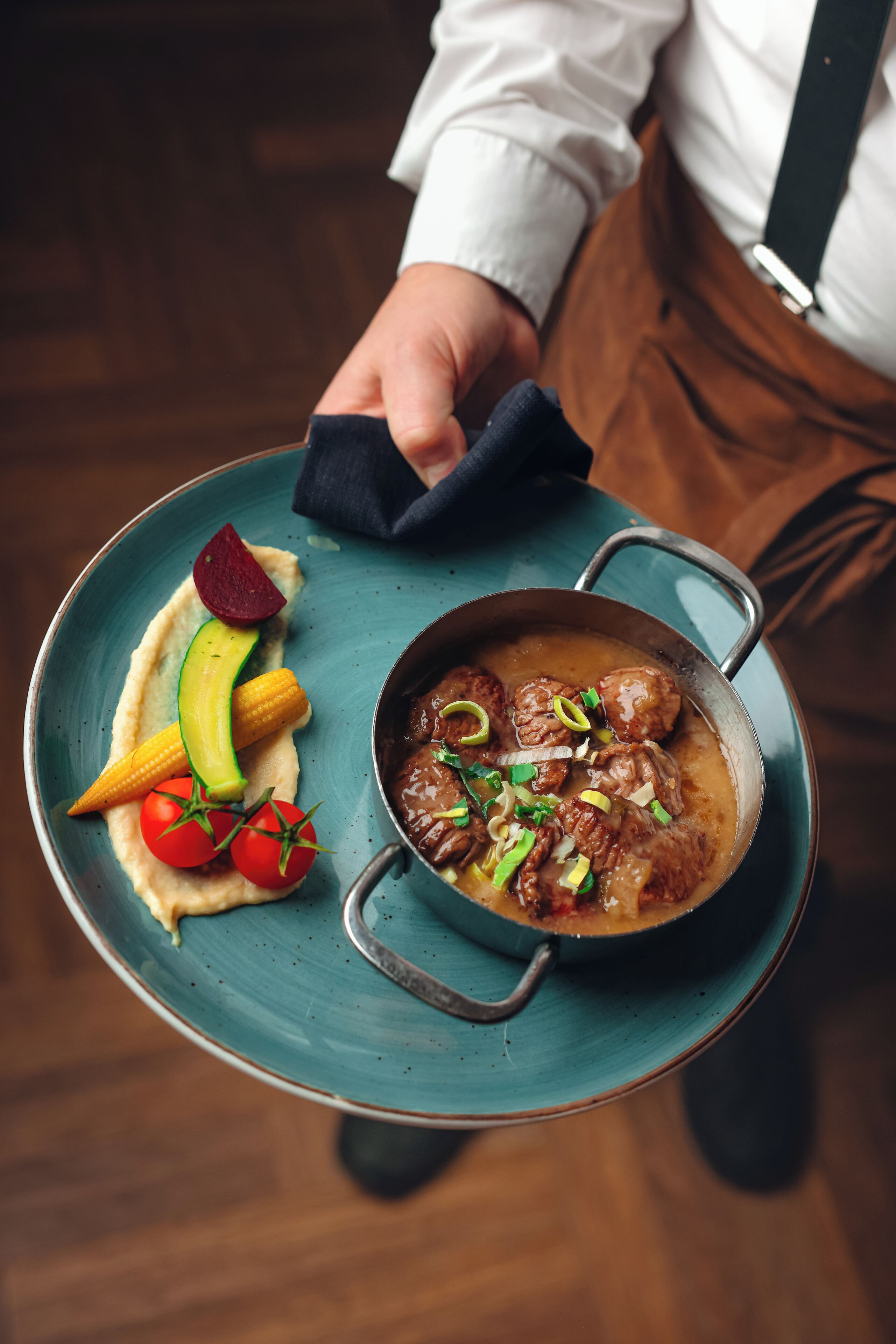 A person holding a plate with a meat dish and vegetables.
