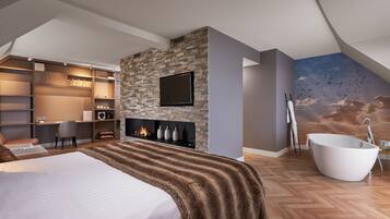 A modern bedroom with a large bed, a fireplace, a TV, a bathtub, and a mural of birds flying.
