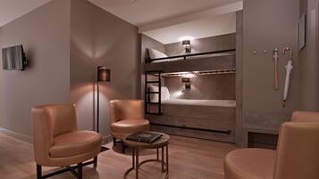 A modern room with a bunk bed, two leather chairs, a small round table, and a floor lamp.