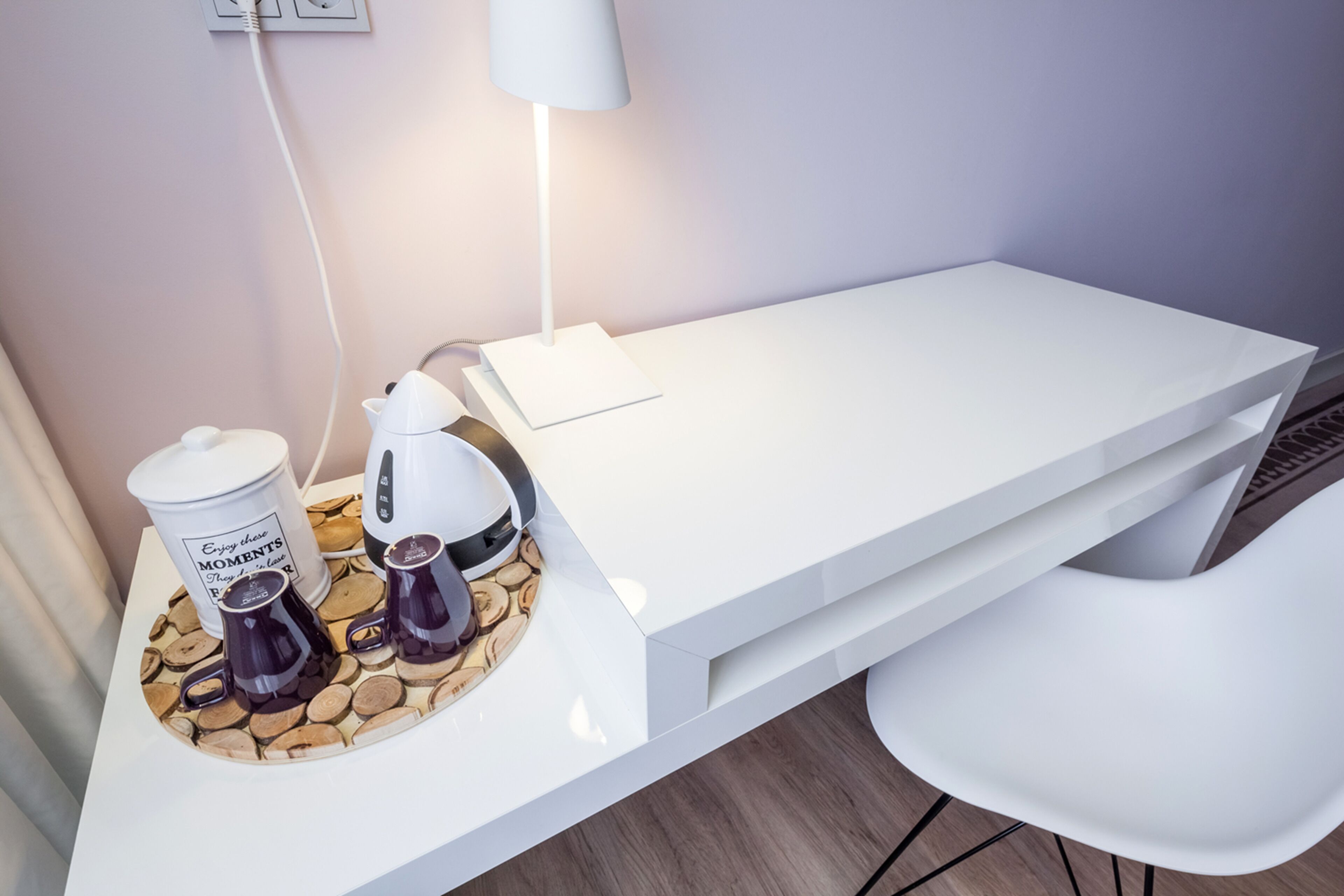 Ein moderner, weißer Schreibtisch mit Kaffeemaschine, zwei Tassen und einer Dose mit einer Nachricht.