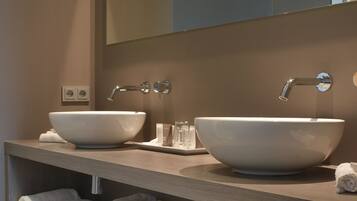 Een moderne badkamer met twee grote witte wasbakken, een spiegel en een plank met netjes opgevouwen handdoeken.