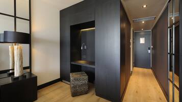 A modern hotel corridor with a wooden floor, a black wall unit with a sink, and a zebra-patterned ottoman.
