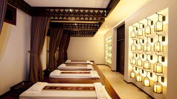 Un salón de spa con varias camillas alineadas a lo largo de una pared, techo de madera y una lámpara fijada en la pared.