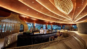 A modern bar area with a curved seating arrangement, a central bar counter, and a distinctive ceiling design with integrated lighting. - Graceland Khaolak Beach Resort (Takua Pa)