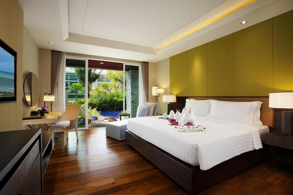 A modern hotel room with a large bed, a desk, and a view of the ocean.