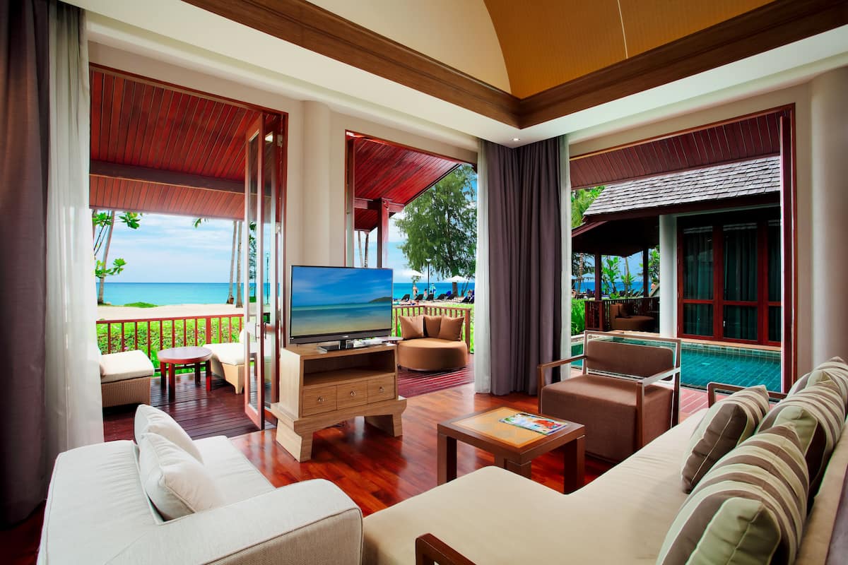 A spacious living area with a television, comfortable seating, and a view of the ocean.