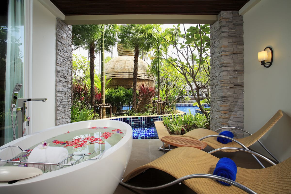 A spa area with a hot tub, lounge chairs, and a pool.