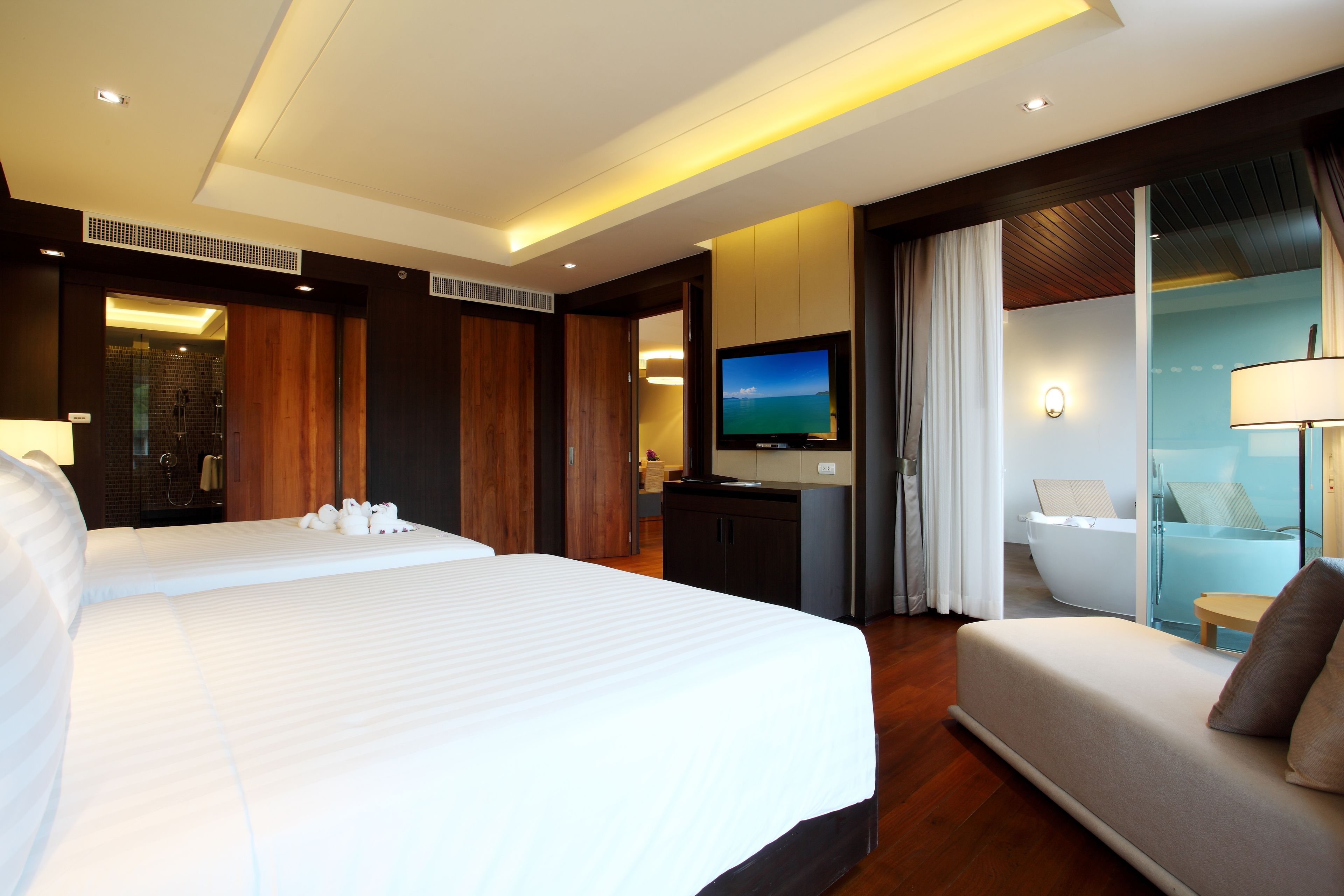 Une chambre d’hôtel avec deux lits, une télévision, un canapé et une salle de bain avec baignoire.
