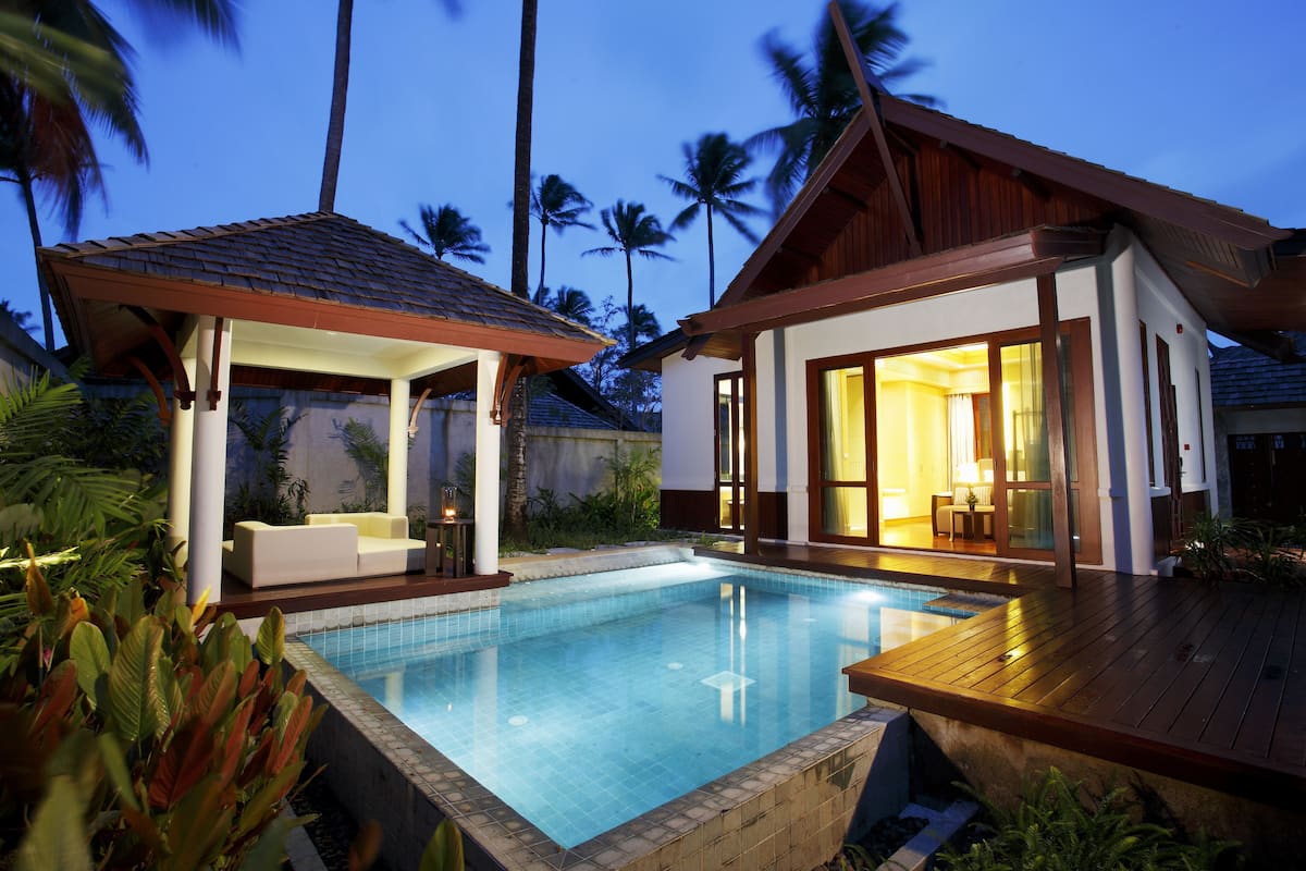 A poolside area with a covered seating area and a building with large windows.