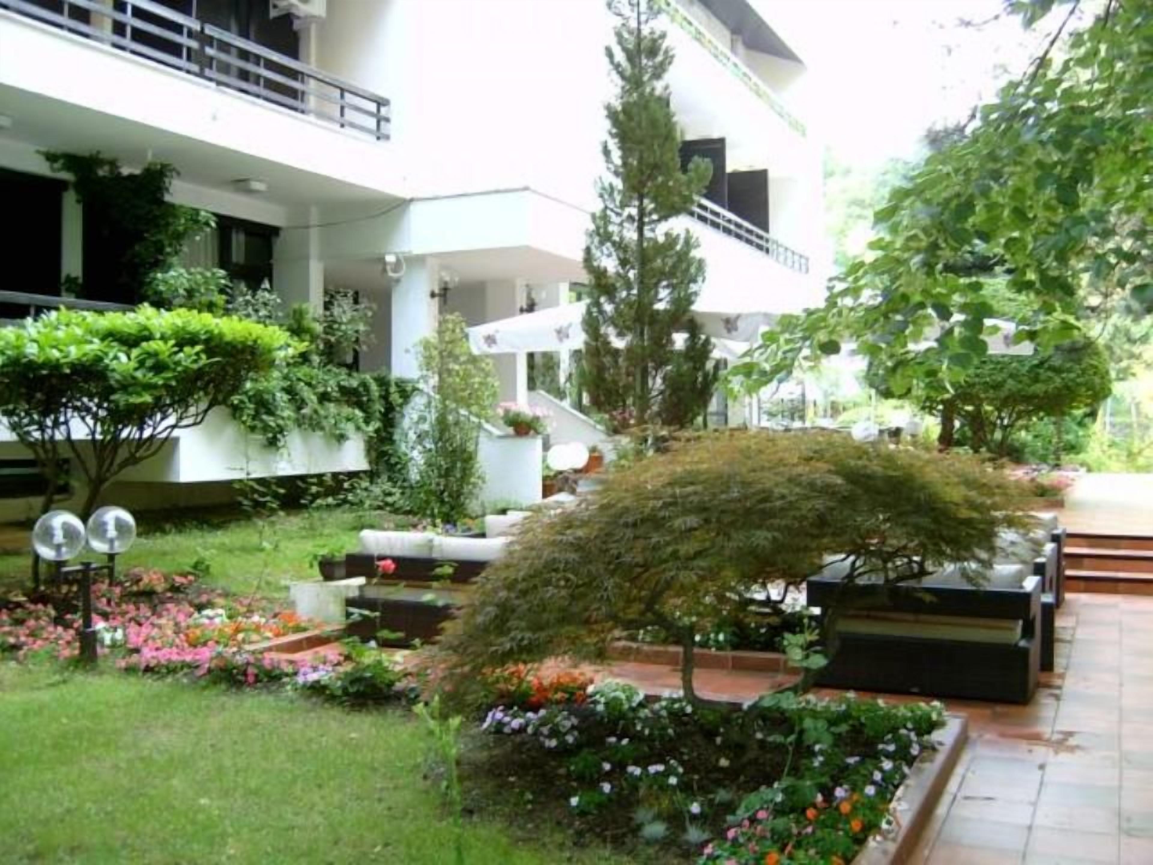 A courtyard with a variety of plants and a bench.