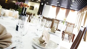 A dining area with tables set for a meal, featuring white tablecloths, clear glassware, and neatly folded napkins. - Pela Hotel Ohrid (Ohrid)