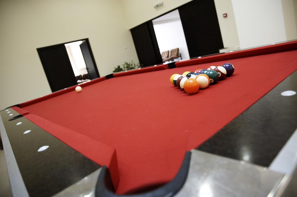 A pool table with balls arranged for a game, a mirror reflecting part of the room, and a door leading to another area.