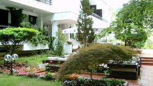 A courtyard with a variety of plants and a seating area. - Pela Hotel Ohrid (Ohrid)