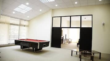 Una habitación con mesa de billar, una mesa de vidrio y vistas a través de un umbral.