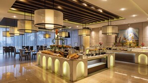 Un vestíbulo de hotel moderno con un bufé central, área de estar e iluminación contemporánea.