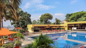 Un hotel con piscina, mobiliario exterior y palmeras.