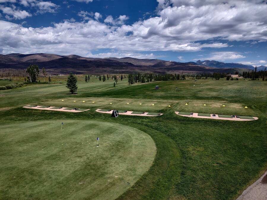 A golf course with bunkers, flags, and a mountainous backdrop.