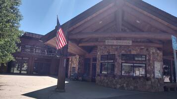 A wooden building with a stone facade, labeled "Box Office," and an American flag.