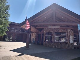 A wooden building with a stone facade, labeled "Box Office," and an American flag.
